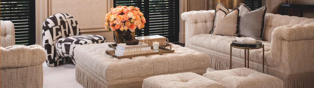 The Comfort of Curves- Living room with beige sofa, ottoman, and coffee table with decorative items.