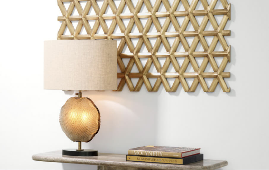 Decorative lamp on a table with a geometric wall art piece in the background
